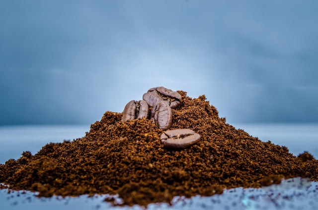 a pile of coffee grounds with some coffee beans