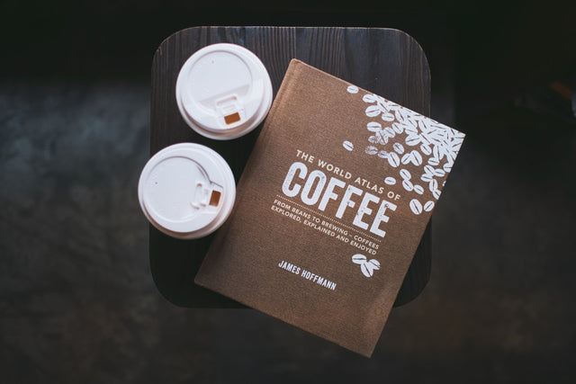 a book about coffee on a table next to two coffee cups
