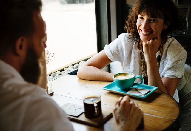 Two people enjoying cups of coffee in a café while chatting. 