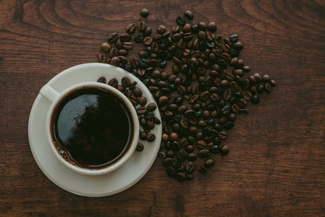 cup of black coffee with coffee beans next to it