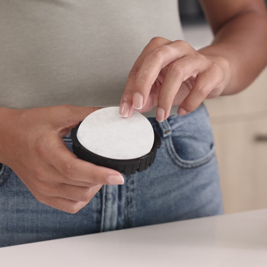 Placing a round AeroPress paper filter into the filter cap